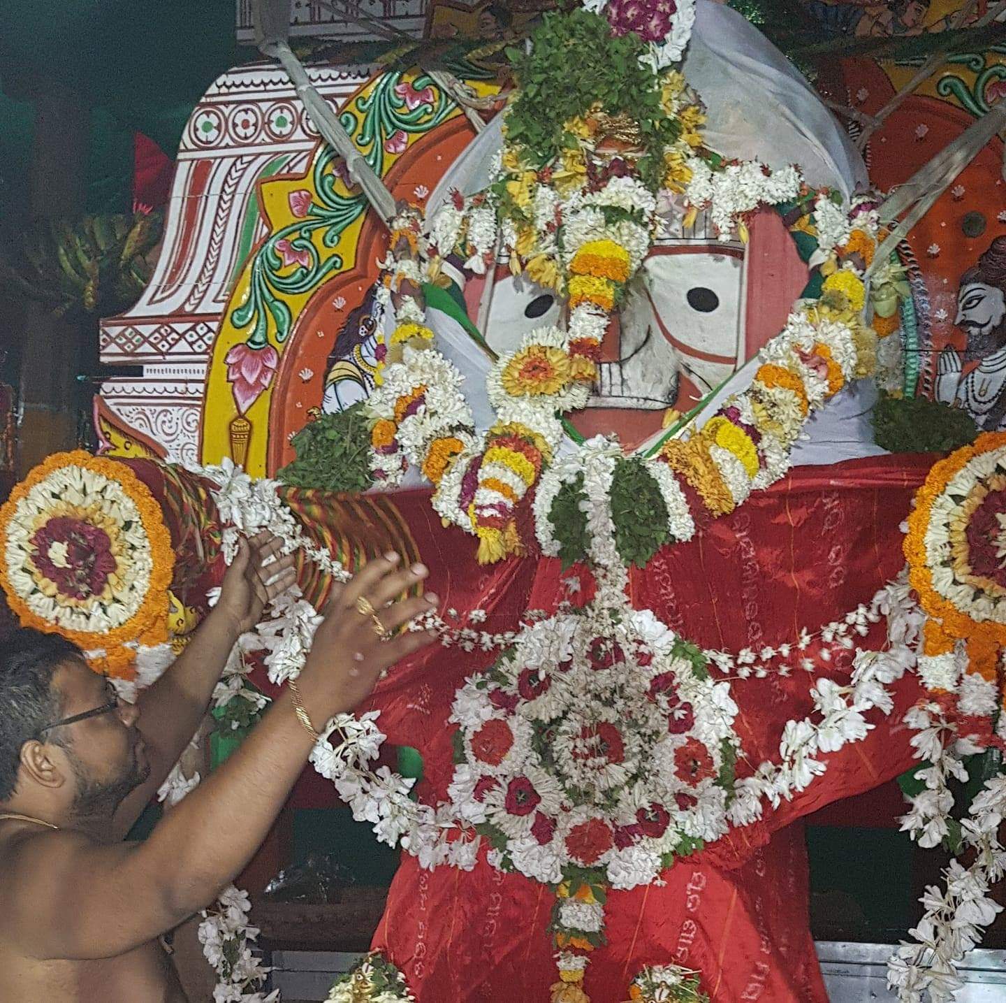 A servitor offering garlands to Lord Balabhadra during the evening seva on the chariot