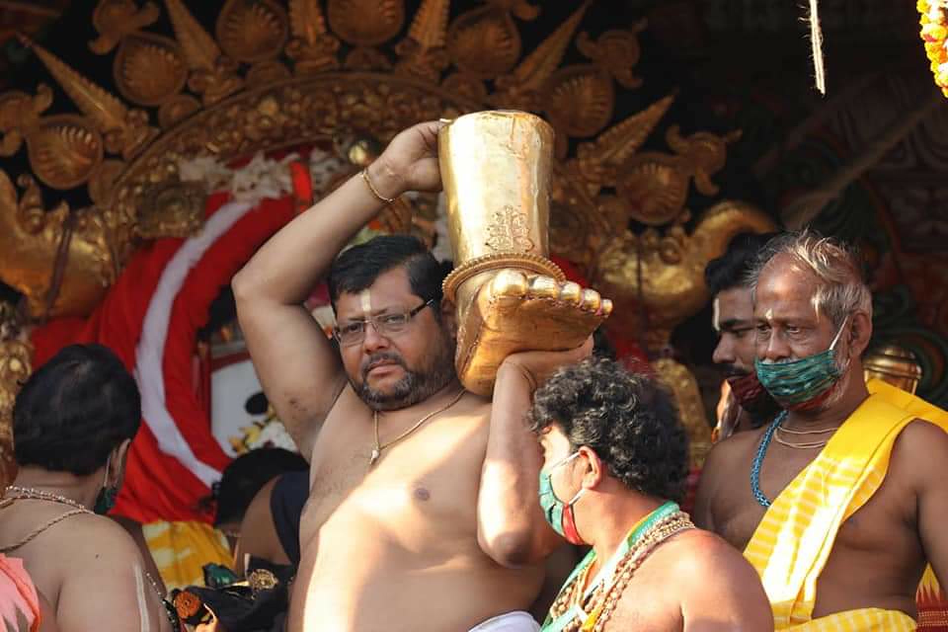 A sevak carrying the golden hand of the deity during ritual seva at the chariot in Puri