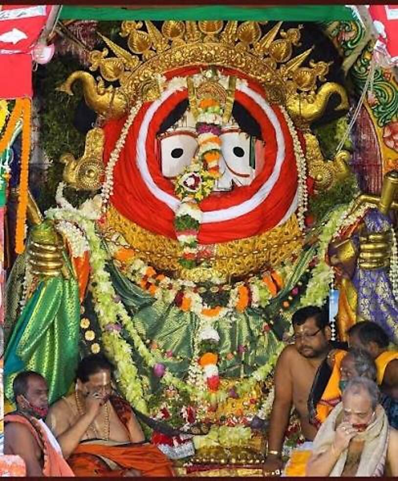 The deities in festive besha, framed by golden ornaments and fresh garlands